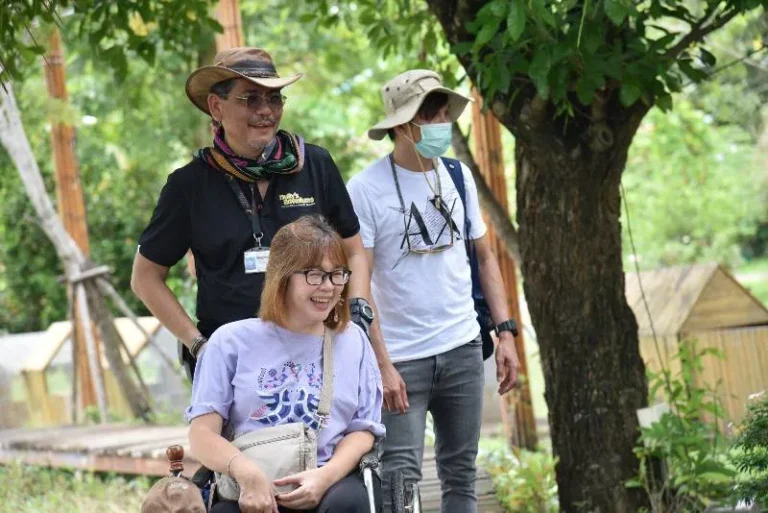 Three people enjoying an outdoor accessible tour, including a smiling wheelchair user