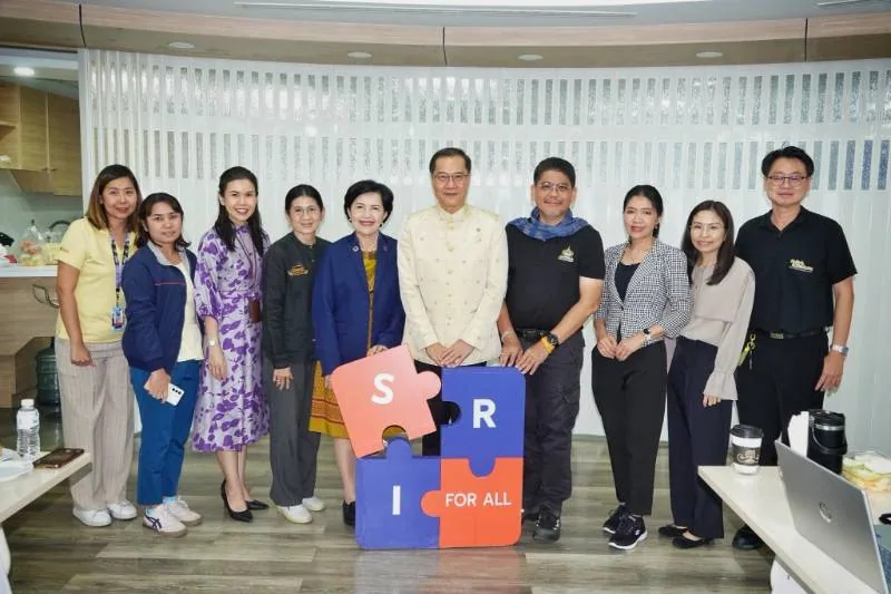 Group photo of professionals standing beside a colorful “SIR FOR ALL” puzzle display during an accessibility-focused meeting