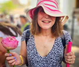 Joyful moments at Wat Po—where tradition, beauty, and accessibility come together A smiling blind traveler holding a pink lotus flower and walking cane at Wat Po temple