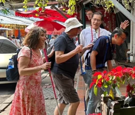 Exploring Chatuchak—Bangkok’s iconic weekend market made accessible for all A group of blind and sighted travelers walking together through Chatuchak Market, surrounded by plants and stalls
