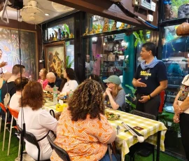 After the market—shared meals and warm connections in Bangkok’s vibrant cultural hub A group of travelers enjoying food and conversation at a lively indoor venue near Chatuchak Market