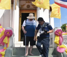 Exploring with confidence! Our experienced guides ensure every step is safe and secure, allowing visually impaired guests A dedicated Thai guide helping an elderly visually impaired male traveller, using a white cane, carefully descend the steep steps of a traditional temple entrance in Ayutthaya, ensuring safe navigation.