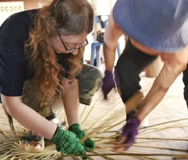 Hands-on heritage: Engaging in the art of traditional basket weaving at the award-winning Baan Dok Bua village. A traveler with a visual impairment learning traditional basket weaving with a local artisan at Baan Dok Bua village.